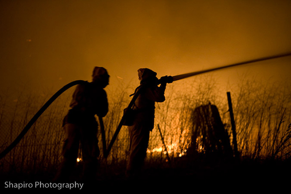 silhouette of firemen with hose lie