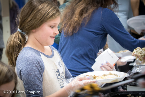 young volunteer serves Thanksgiving dinner