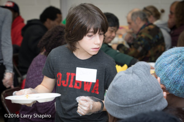 young volunteer serves Thanksgiving dinner