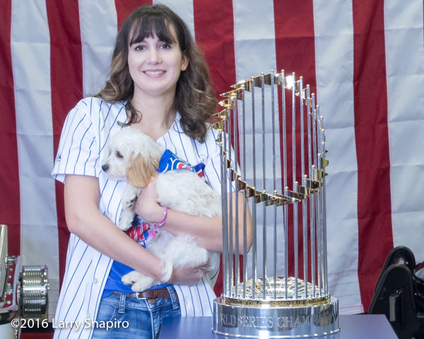 Cubs fan with dog and the world series championship trophy