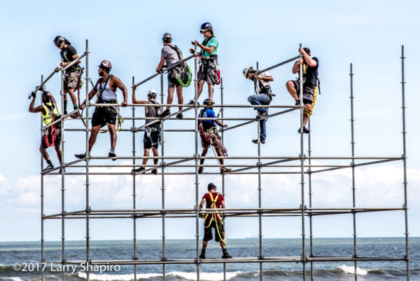 workers scattered across steel pipes on the beach