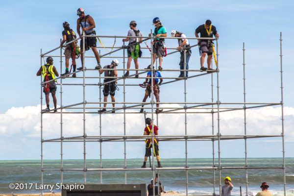 workers scattered across steel pipes on the beach